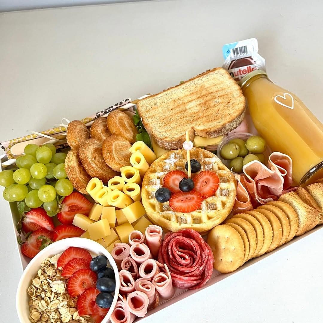 Caja Sorpresa de DesayunoIncluye jugos, panecillos y frutas frescas en una caja decorativa.