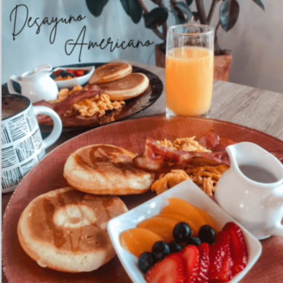 Desayuno AmericanoPanqueques con miel, huevos revueltos y café.